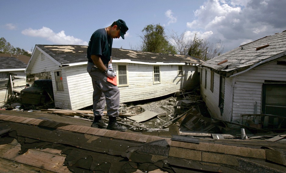 A firefighter makes his way across debris to place a red sticker on a flood-damaged home in New Orleans, October 1, 2005.
