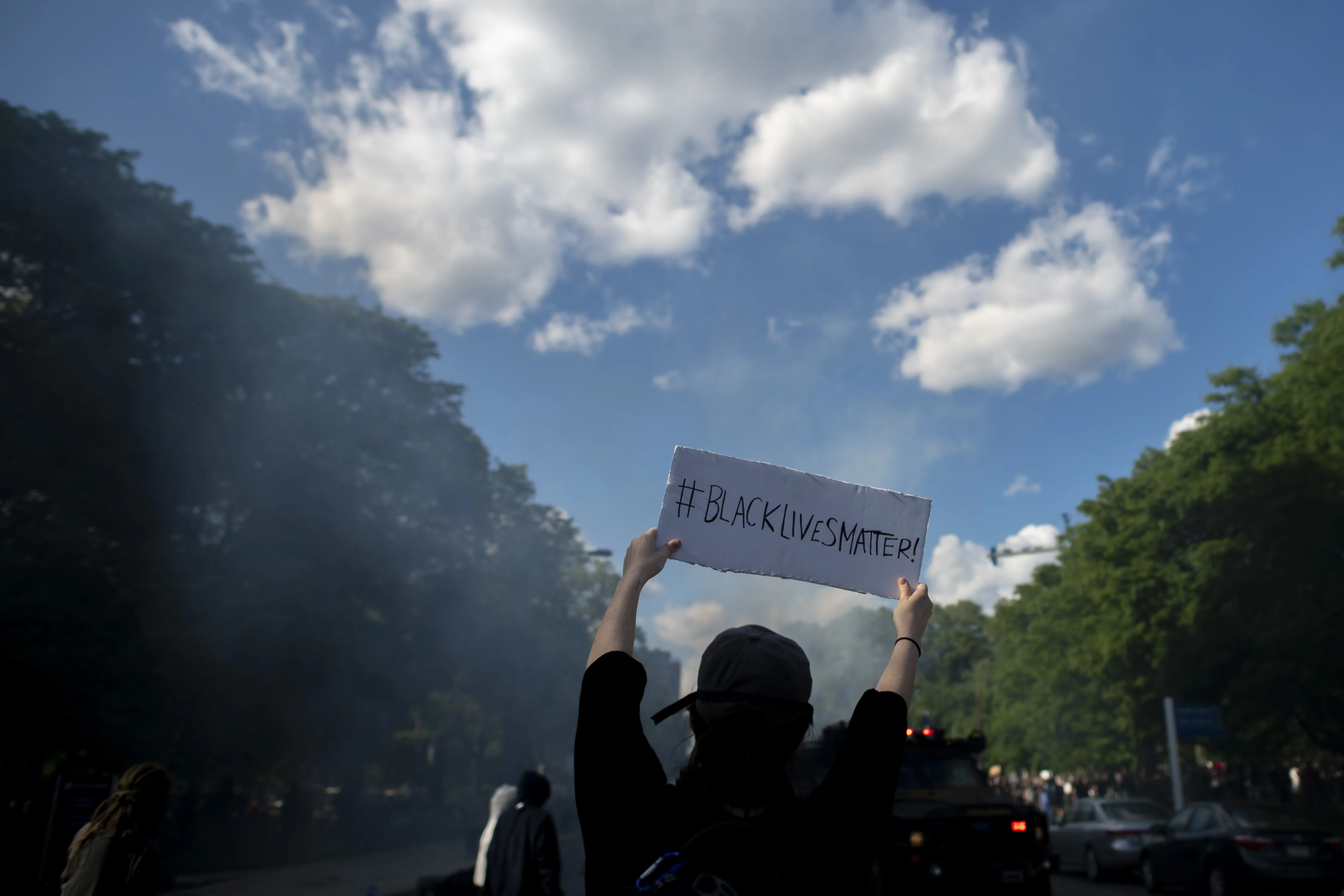 A protestor holds a sign stating "Black Lives Matter" towards police shooting tear gas after a march through in Philadelphia on June 1.