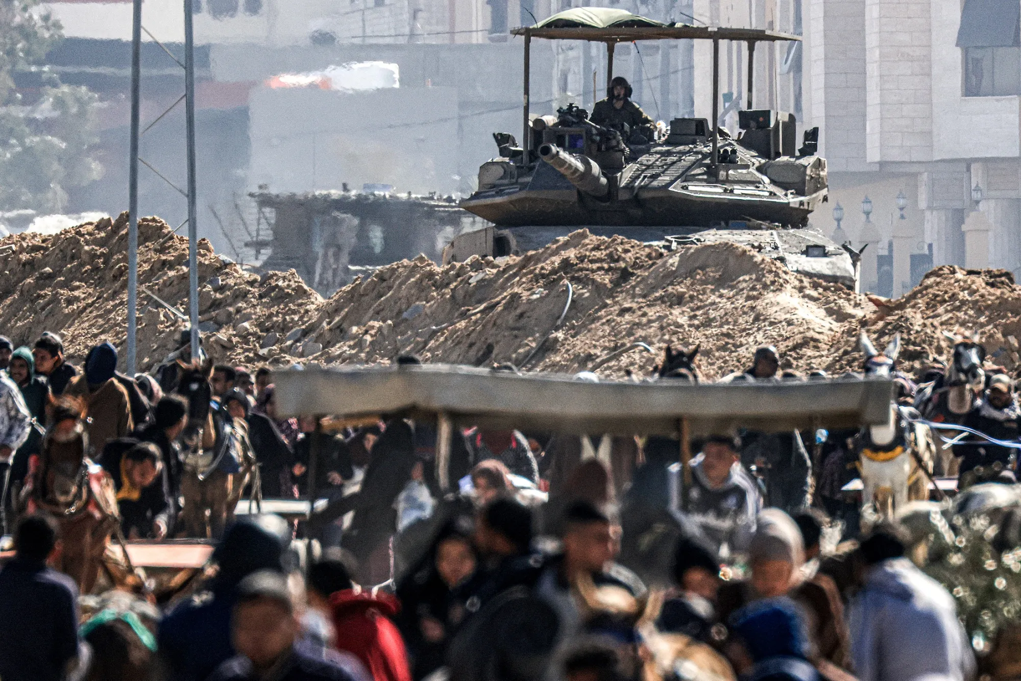 Displaced Palestinians pass an Israeli tank in southern Gaza on Jan. 30.
