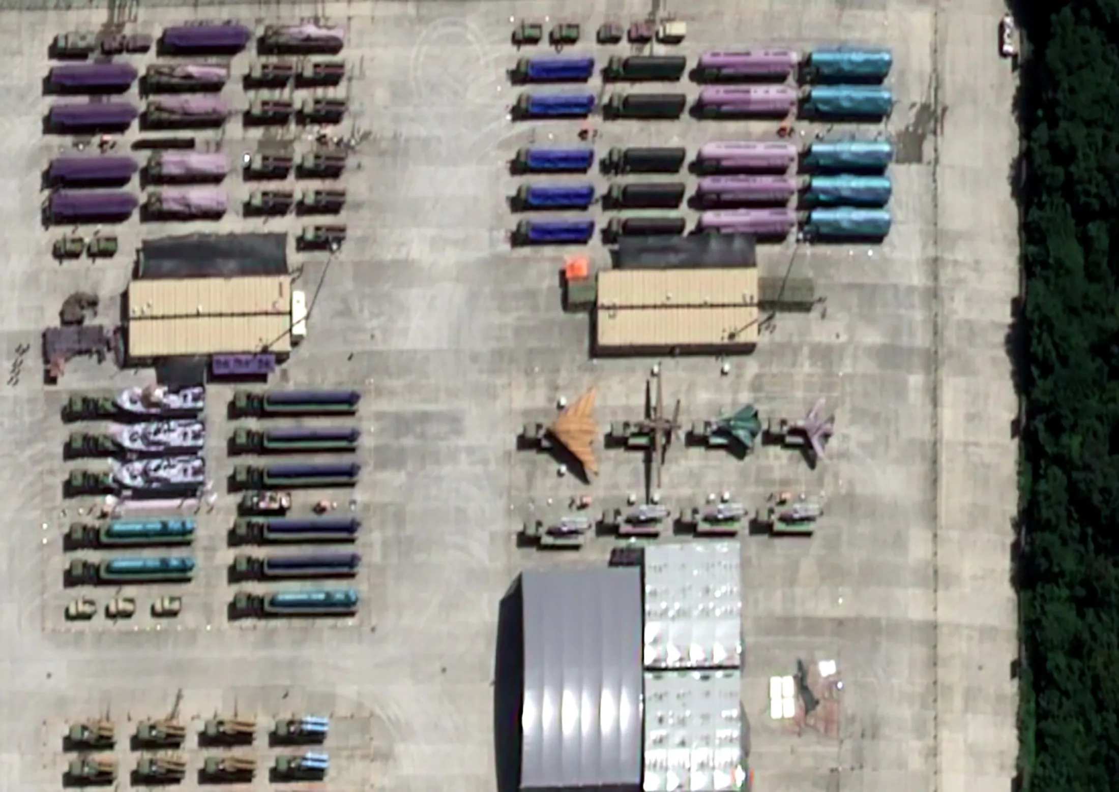 Військова техніка в зоні збору за межами Пекіна на супутниковому знімку, зробленому 9 серпня, на якому, за словами аналітиків, є безпілотники та ракети, накриті брезентом.