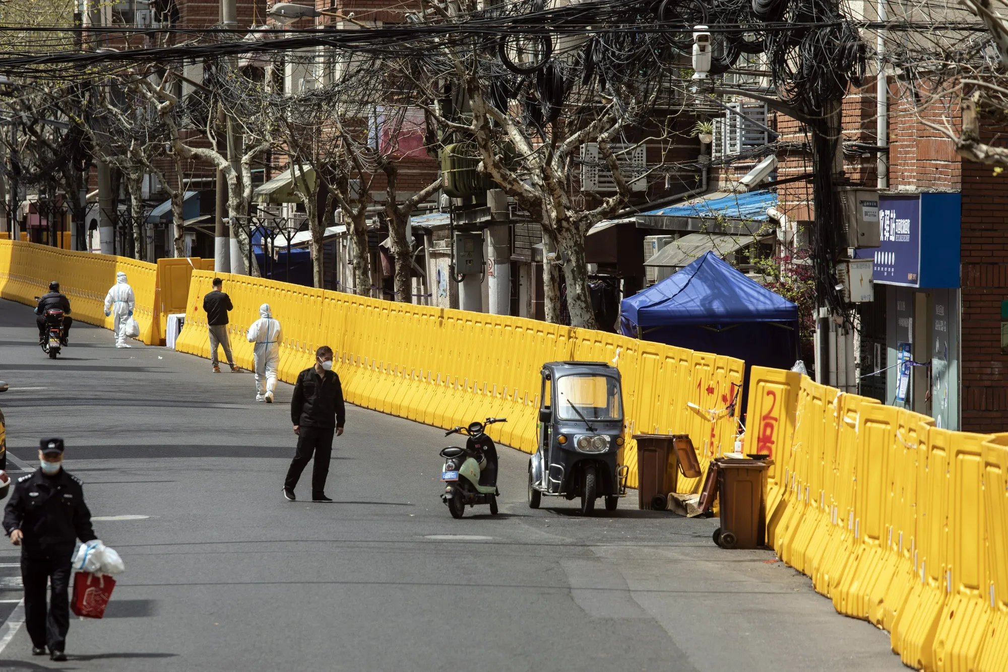 Workers walk past a perimeter wall of a neighborhood under lockdown due to Covid-19 in Shanghai, on March 30.