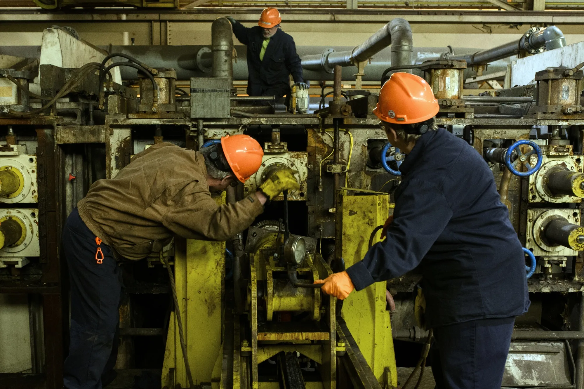 Workers replace a roller that compresses steel at a plant in Midland, Pennsylvania, U.S.