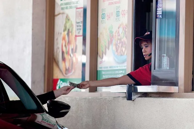 A Carl's Jr. employee gives a customer change through a drive-thru window in San Diego on Sept. 13, 2013