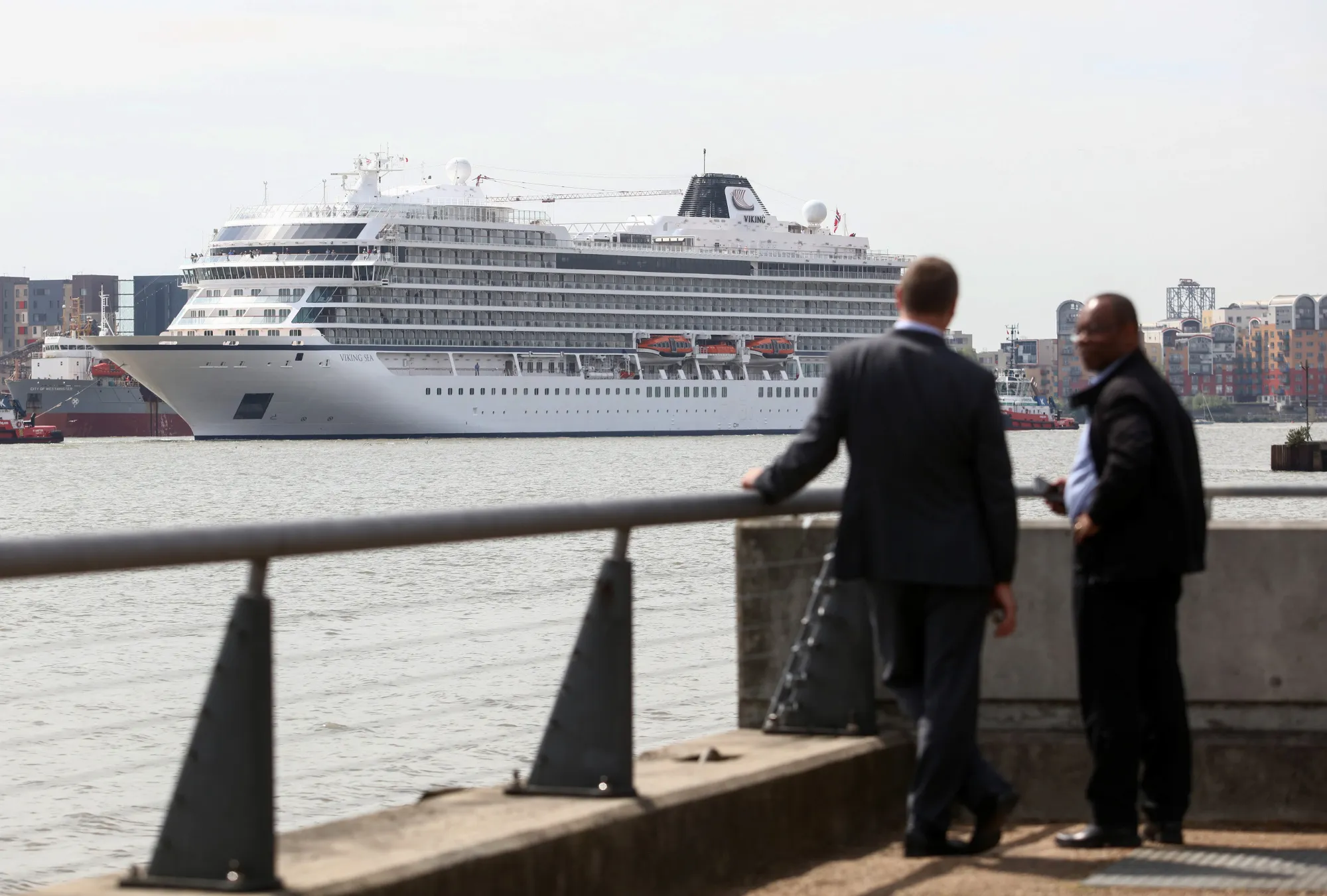 Pedestrians watch as the Viking Sea passes along the River Thames in London.