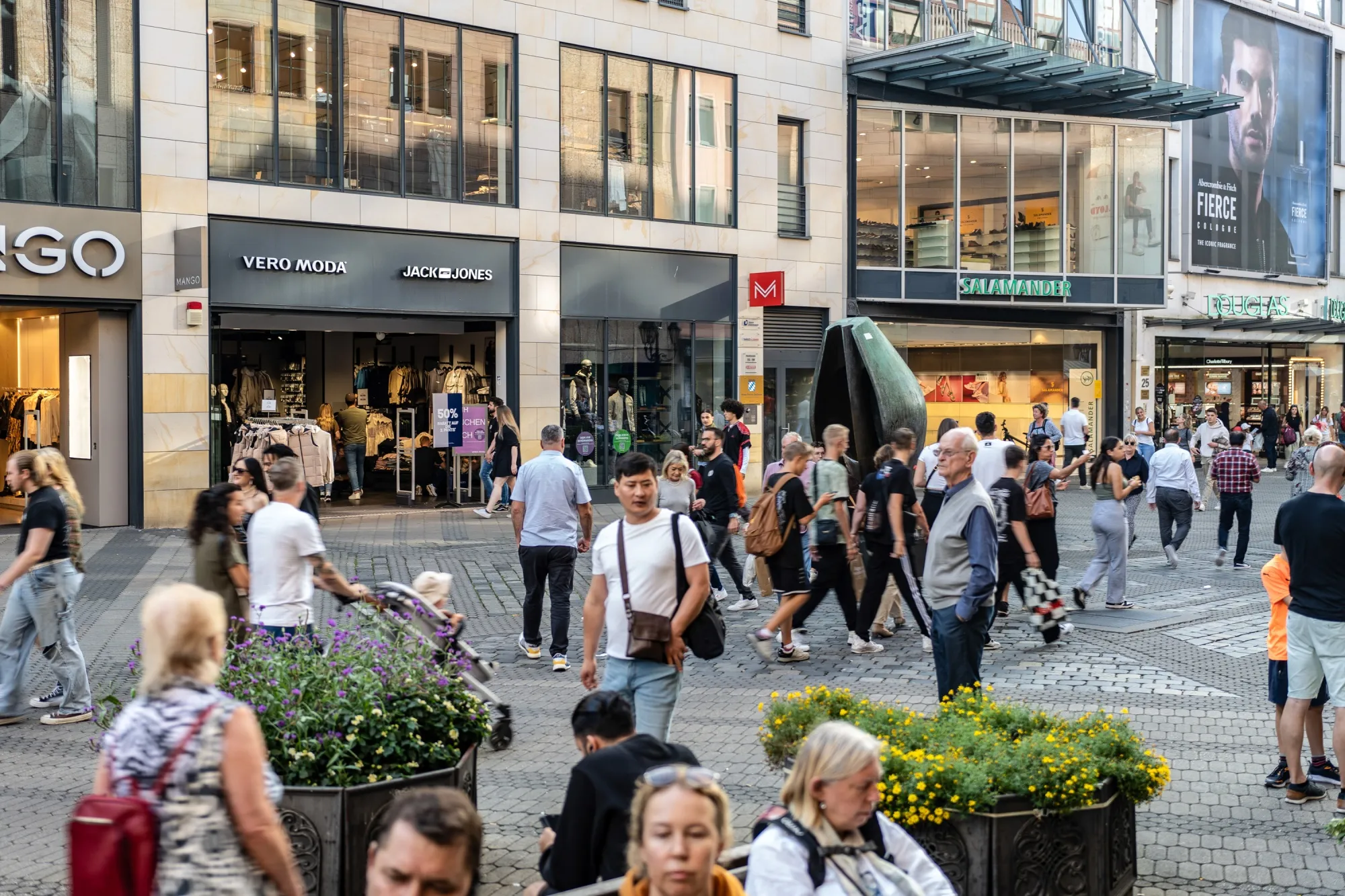 Shoppers walk along a pedestrianized shopping street in Nuremberg, Germany.