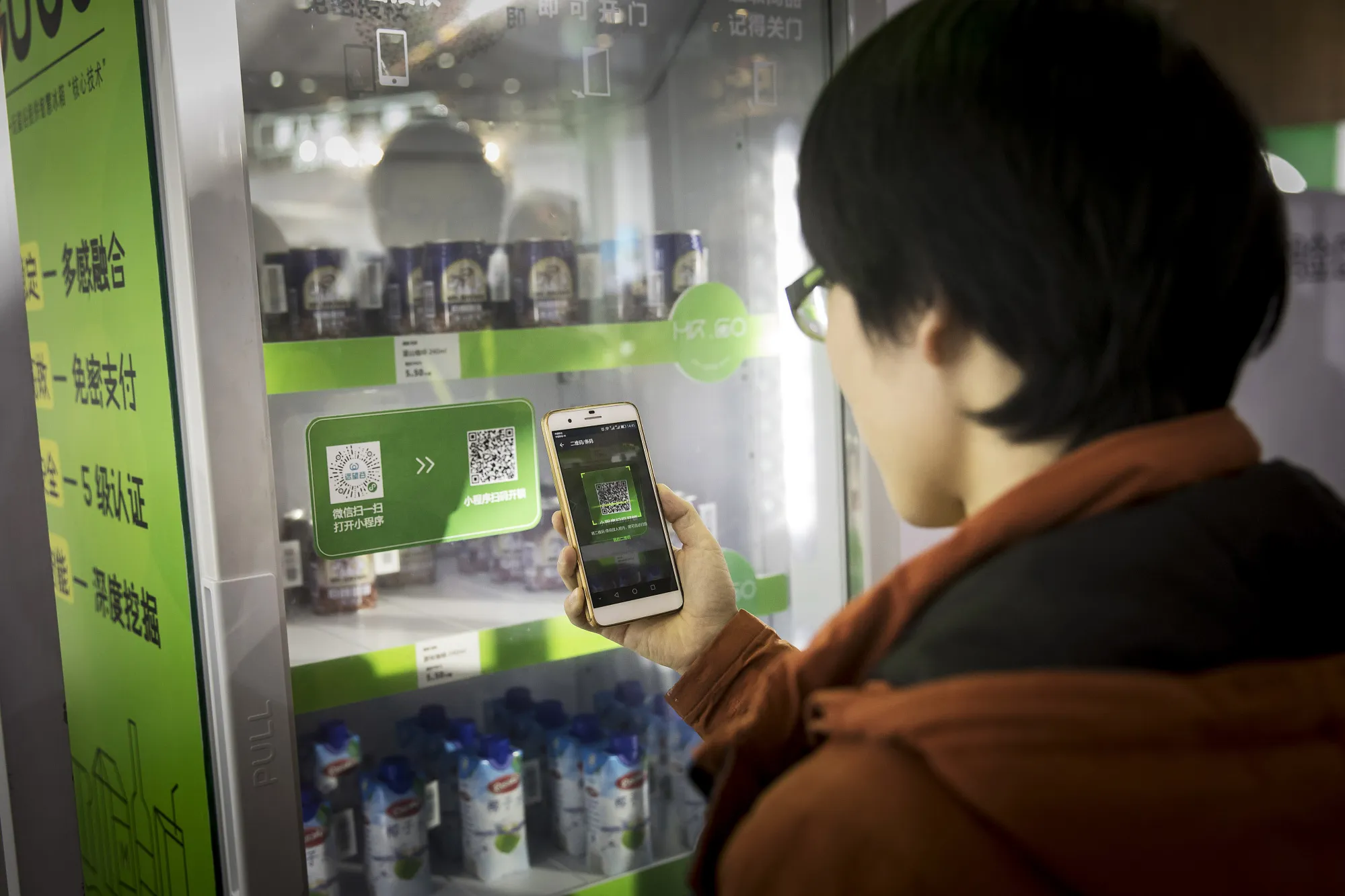 An attendee scans a QR code with his smartphone to purchase a drink from a vending machine at Tencent&nbsp;Holdings Ltd.'s WeChat Open Class Pro conference in Guangzhou, China, on&nbsp;Jan. 15, 2018.&nbsp;