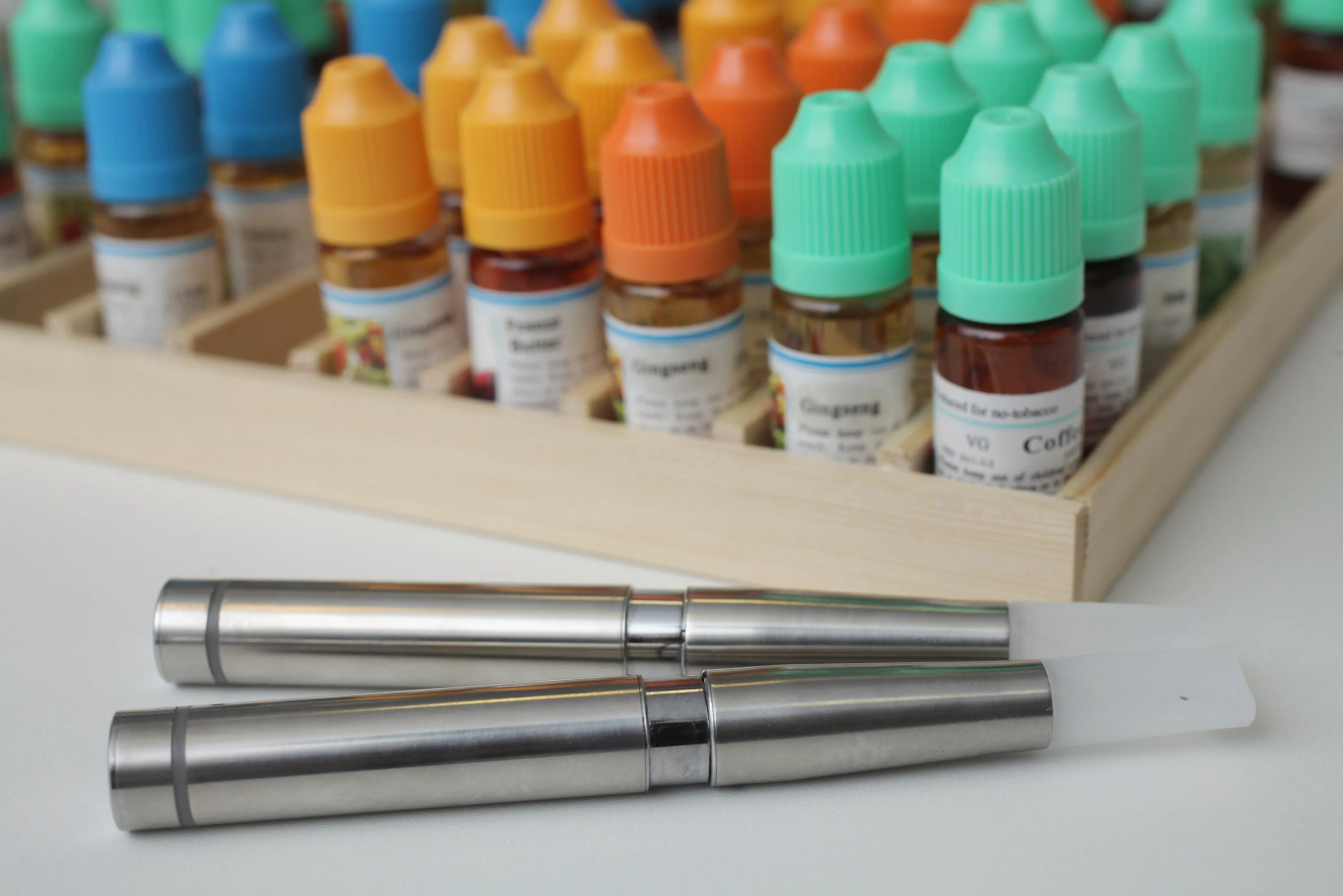 Electronic cigarettes in front of bottles containing flavored liquids.