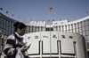 A woman walks past the People's Bank of China (PBOC) headquarters in Beijing, China.