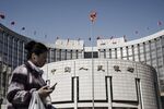 A woman walks past the People's Bank of China (PBOC) headquarters in Beijing, China.