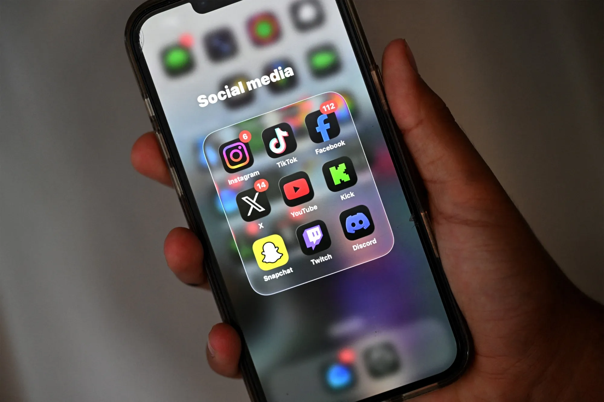 A teenager looks at social media apps on a phone.