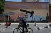 A cyclist rides past a mural of oil pump jacks on the Boulevard de Sabana Grande in Caracas, Venezuela.