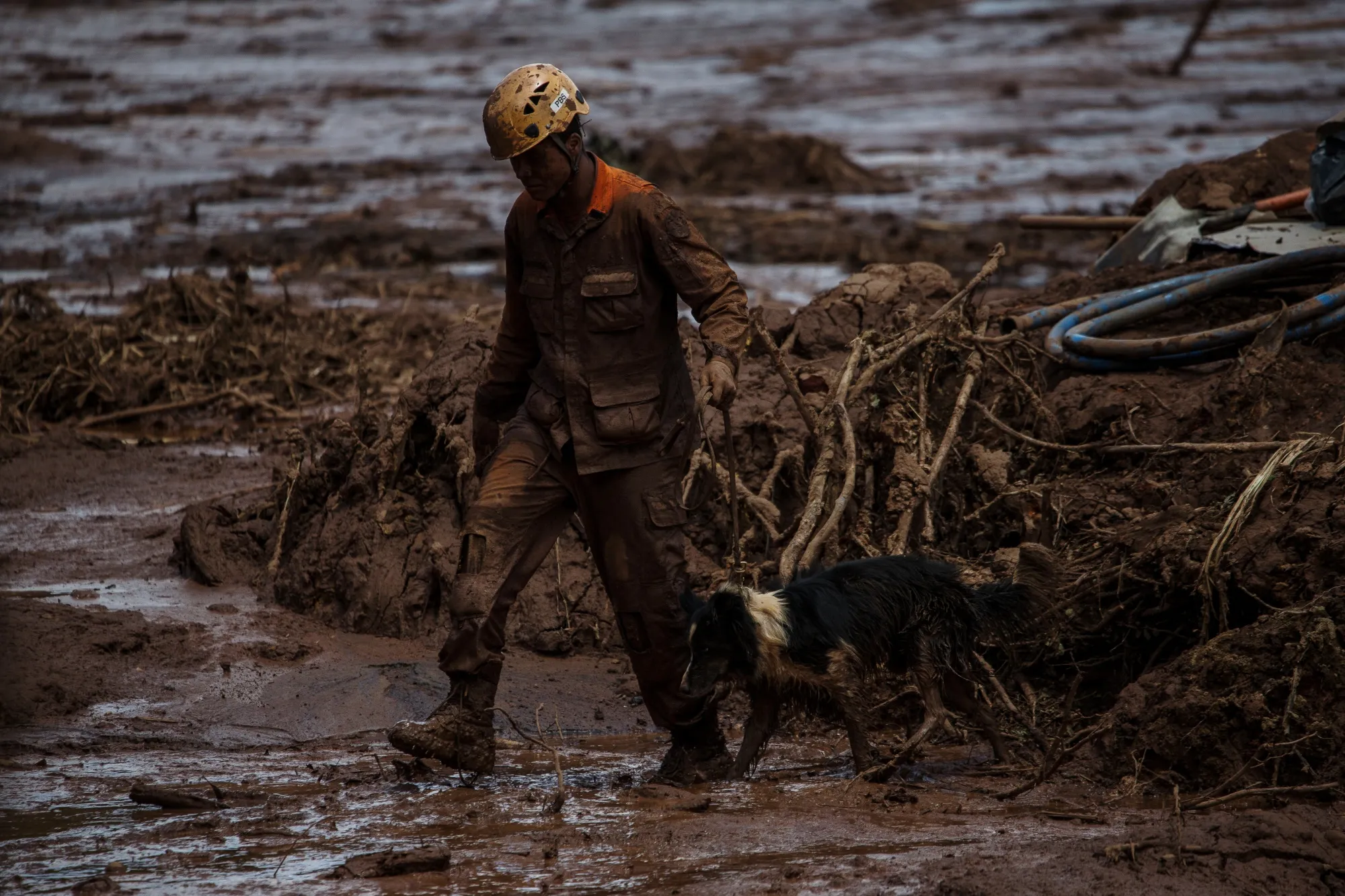 A rescue worker leads a dog through the damage after a Vale SA dam burst in Brumadinho, Minas Gerais state, Brazil, on Jan. 28, 2019.