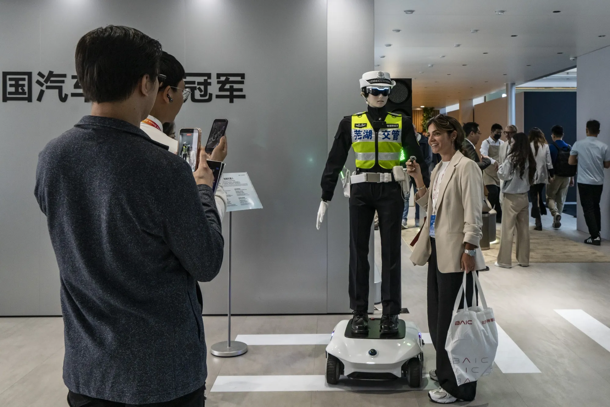 Attendees&nbsp;with a humanoid robot traffic officer at the Beijing Auto Show.