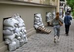 People walk past the Lviv National Art Gallery with windows protected by sandbags.