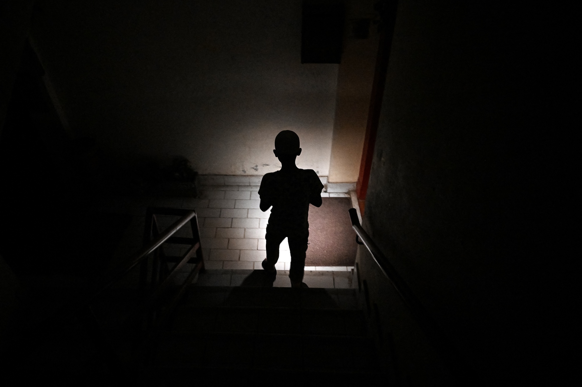 A child uses a mobile phone torch to climb down from his apartment during a power outage in Islamabad on April 15.