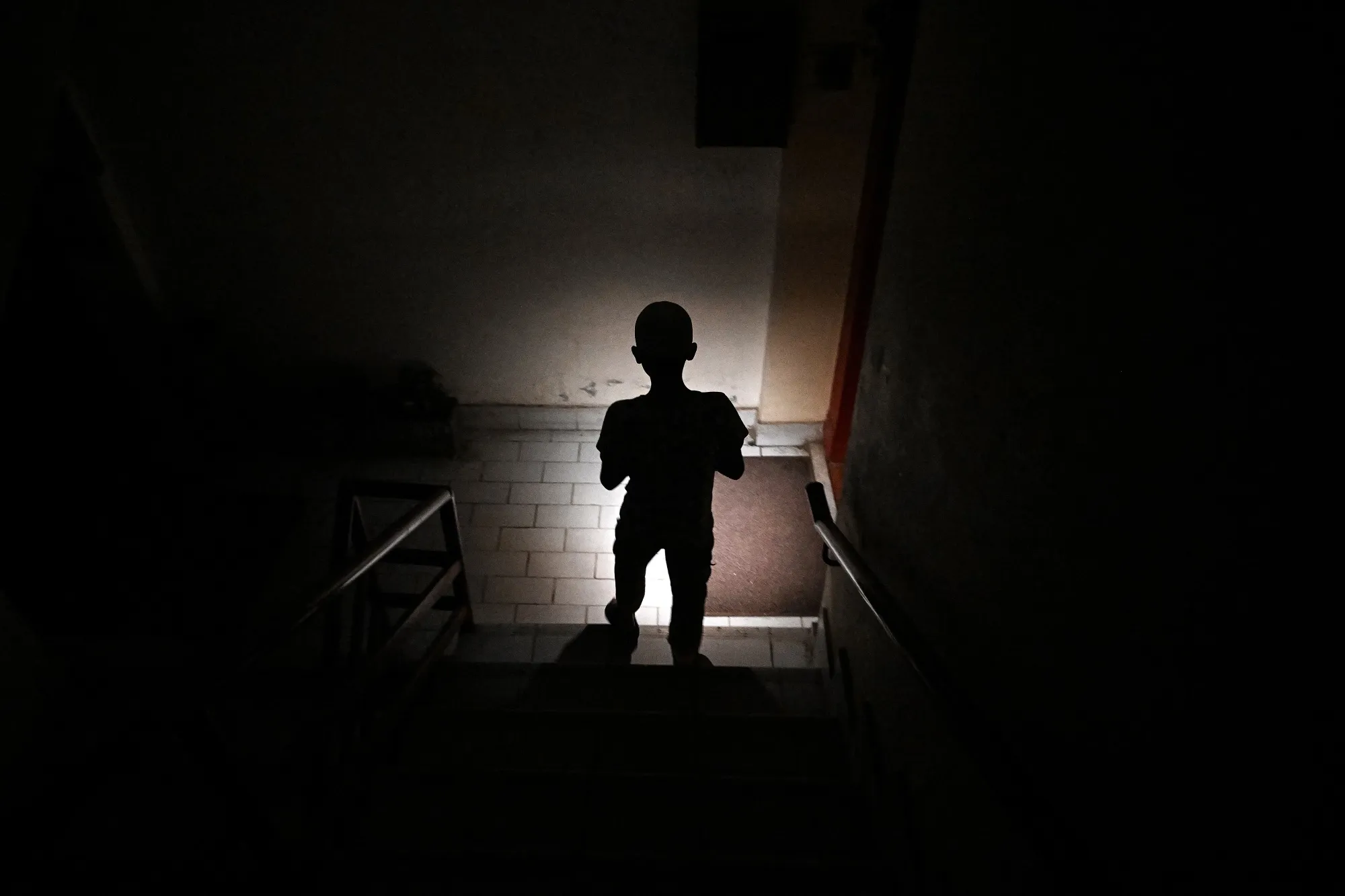 A child uses a mobile phone torch to climb down from his apartment during a power outage in Islamabad on April 15.