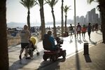 An elderly woman rides a mobility scooter along the beachfront promenade in Benidorm, Spain.