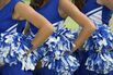 Three cheerleaders in blue and white uniform and pom-poms