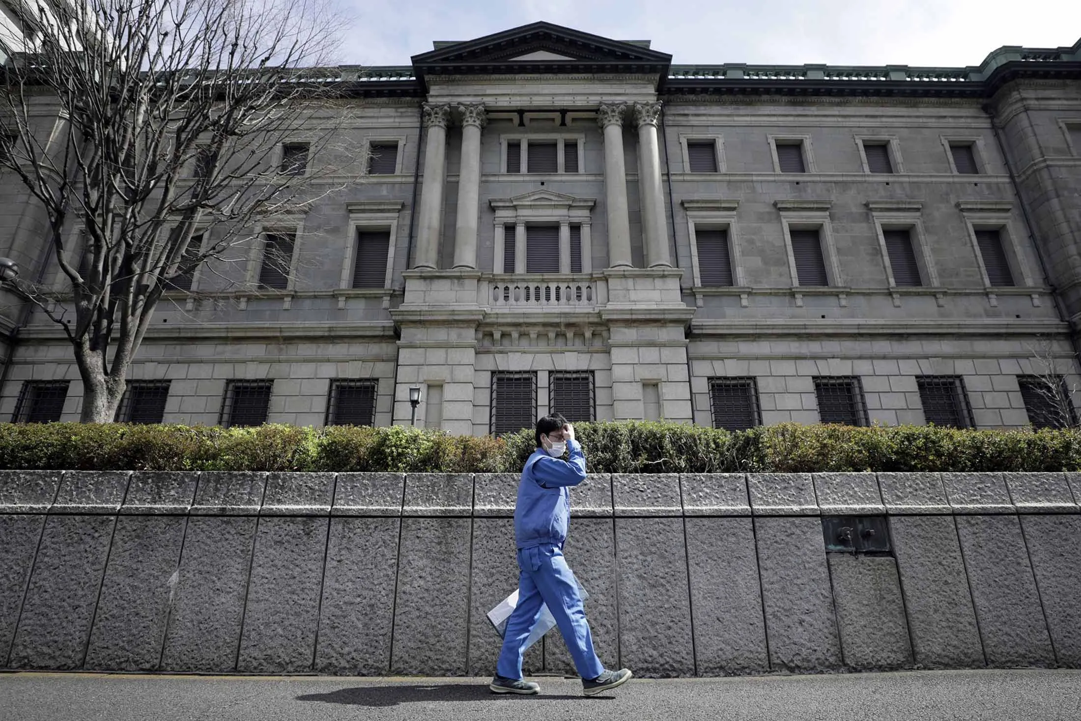 A pedestrian wearing a protective mask walks past the Bank of Japan in Tokyo.