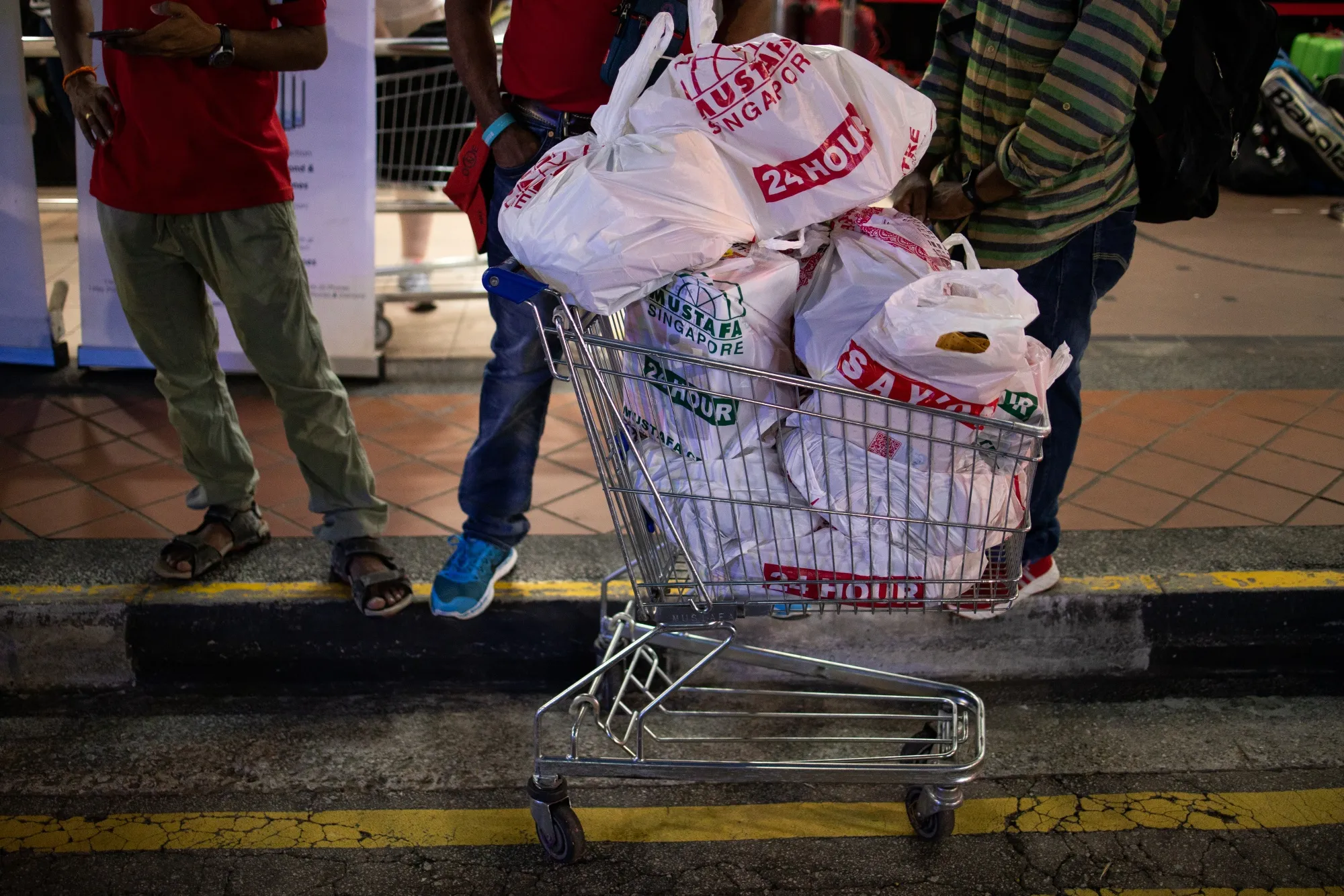A shopping cart filled with bottled water and other products stands outside a supermarket in Singapore, on Saturday, Feb. 8.