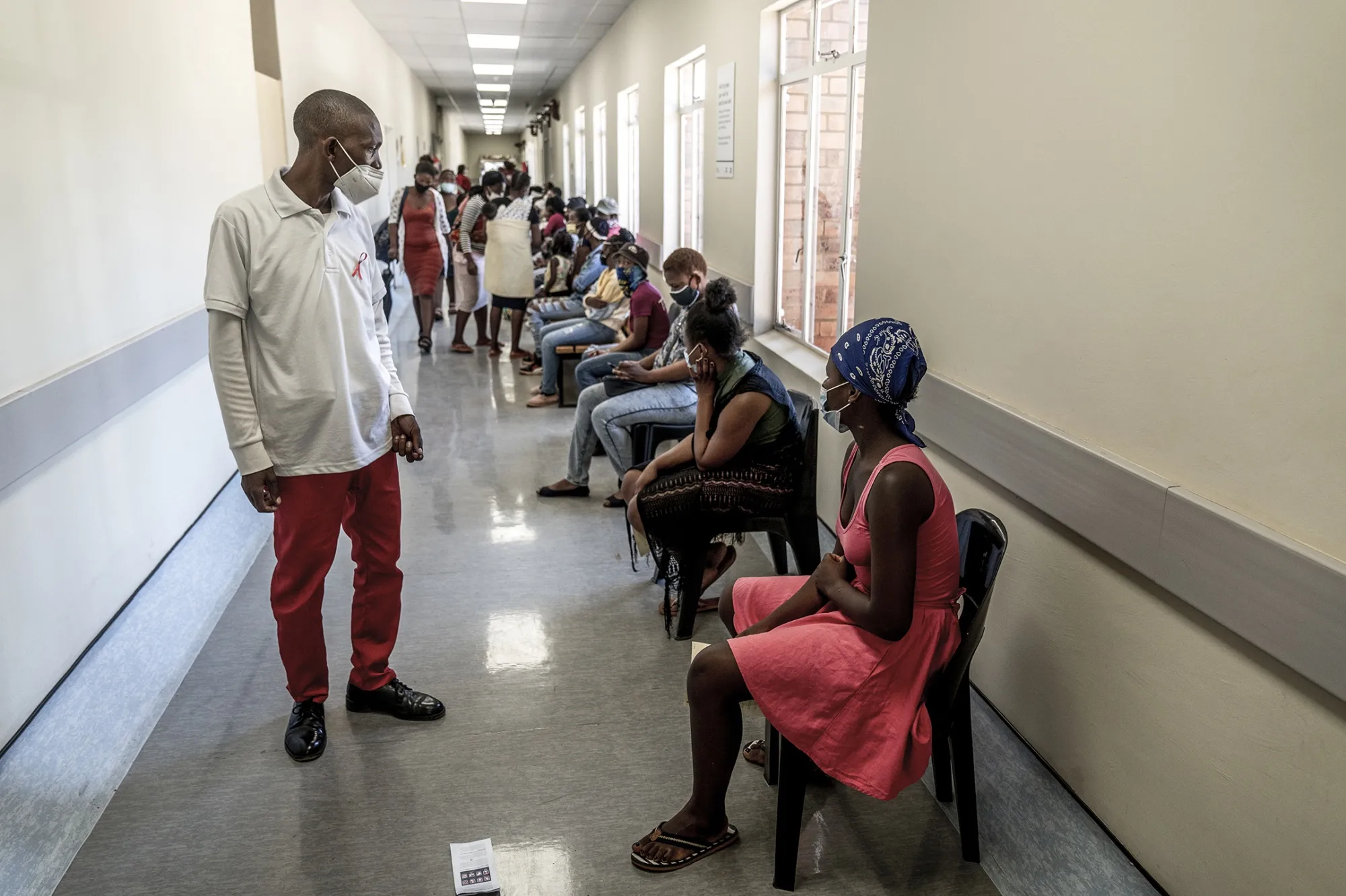 A hospital worker ensures people practice social distancing at the Lenasia South Hospital, near Johannesburg.