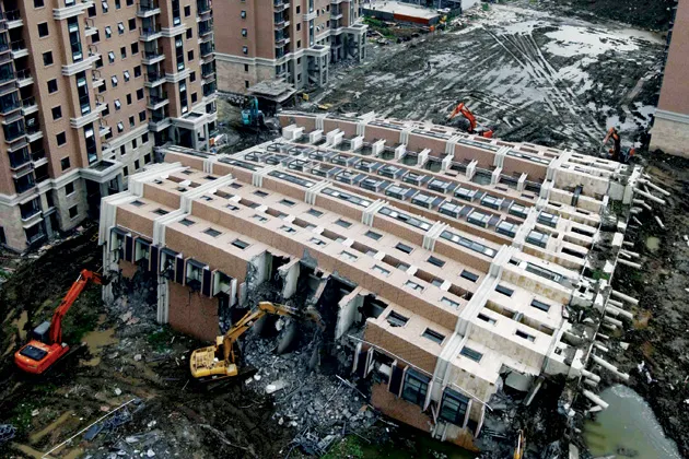 Excavators dismantle a toppled 13-story building in 2009 at the Lotus Riverside apartment complex in Shanghai’s Minhang district. Bad project management, poorly trained workers, and loose monitoring affect the quality of construction