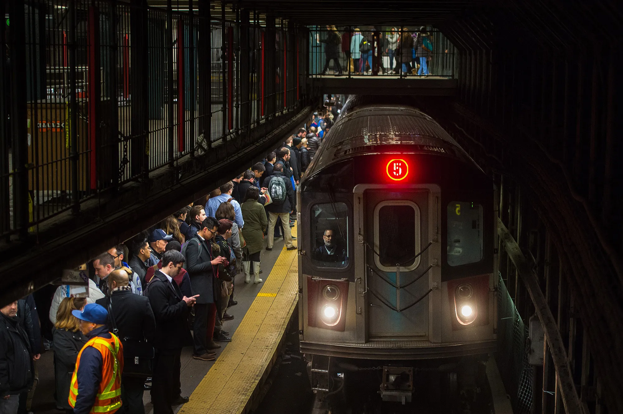 Commuters wait to board a 5 train to arrive at the 14th Street-Union Square subway station in New York.