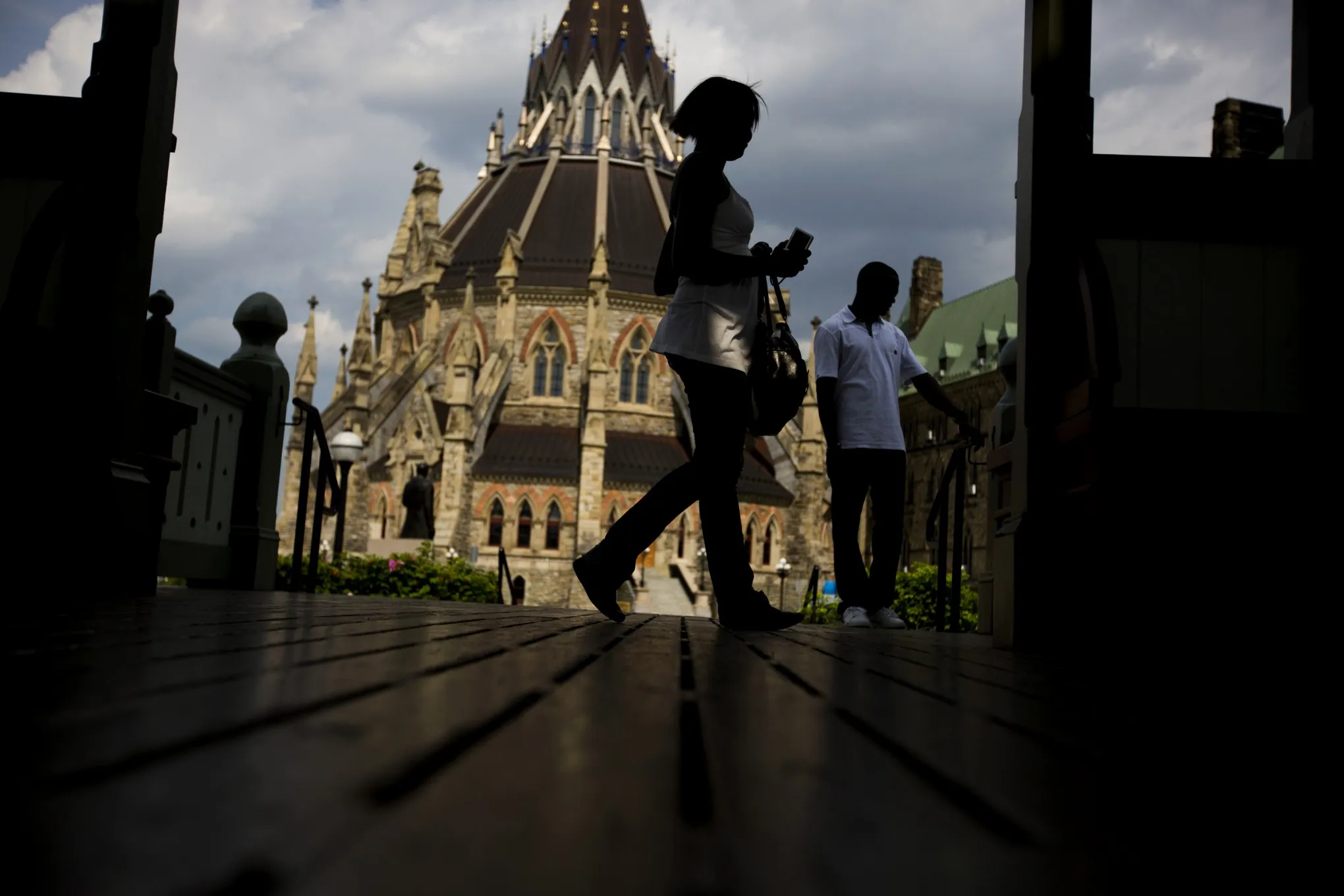Pedestrians walk past the Library of Parliament in Ottawa, Ontario, Canada.
