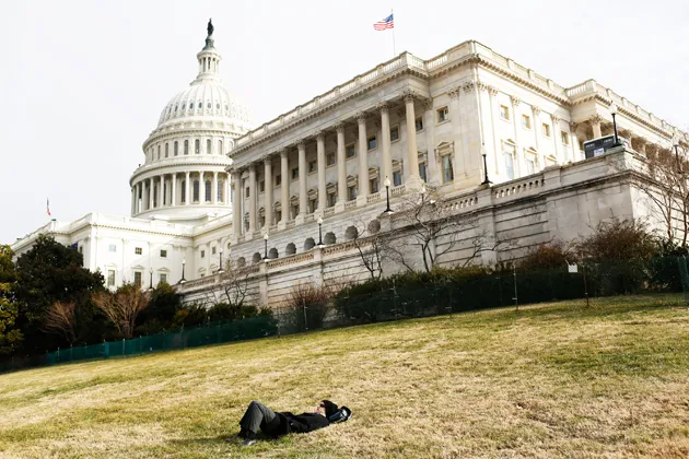 A man lies on the grass in front of the Capitol building during the presidential inauguration in Washington