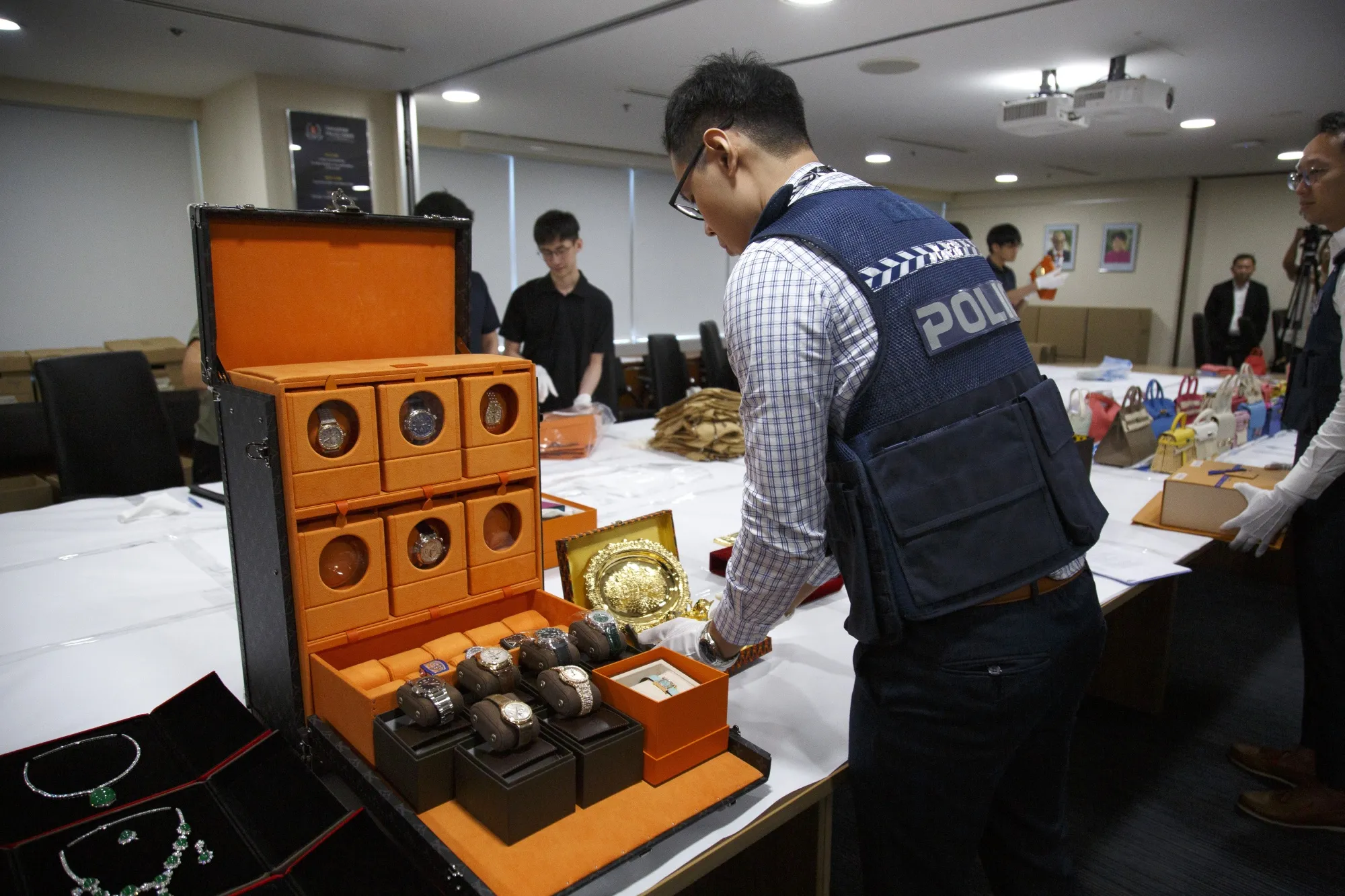 Luxury watches, jade necklaces, luxury handbags and other seized assets displayed in Singapore on Aug. 12.