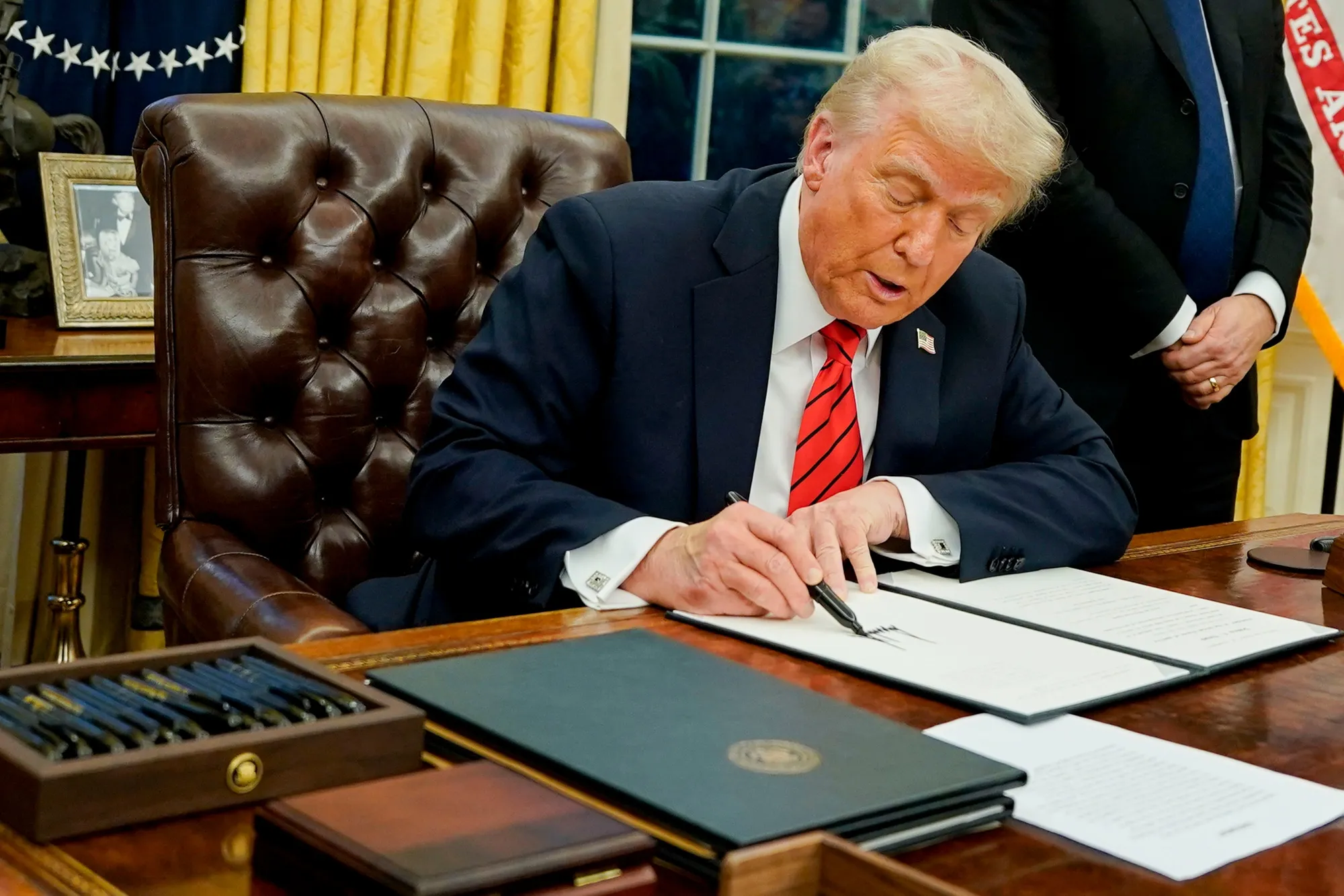 US President Donald Trump signs an executive order in the Oval Office of the White House in Washington, DC.