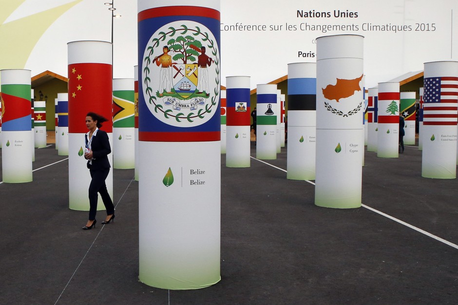 A participant walks amid more than 150 country pillars decorating the entrance of the COP21, United Nations Climate Change Conference, outside Paris.