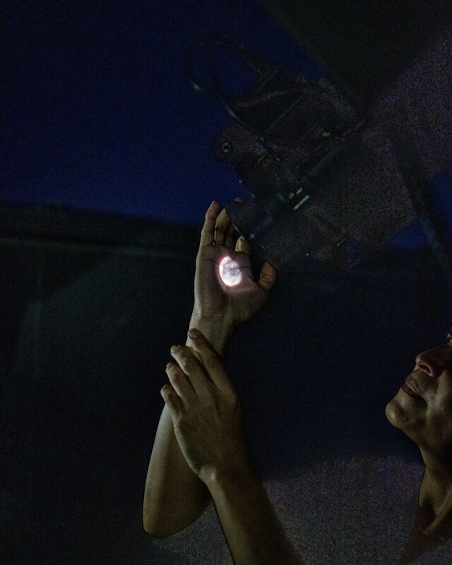 A telescope projects an image of the moon onto Unda-Sanzana’s hand.