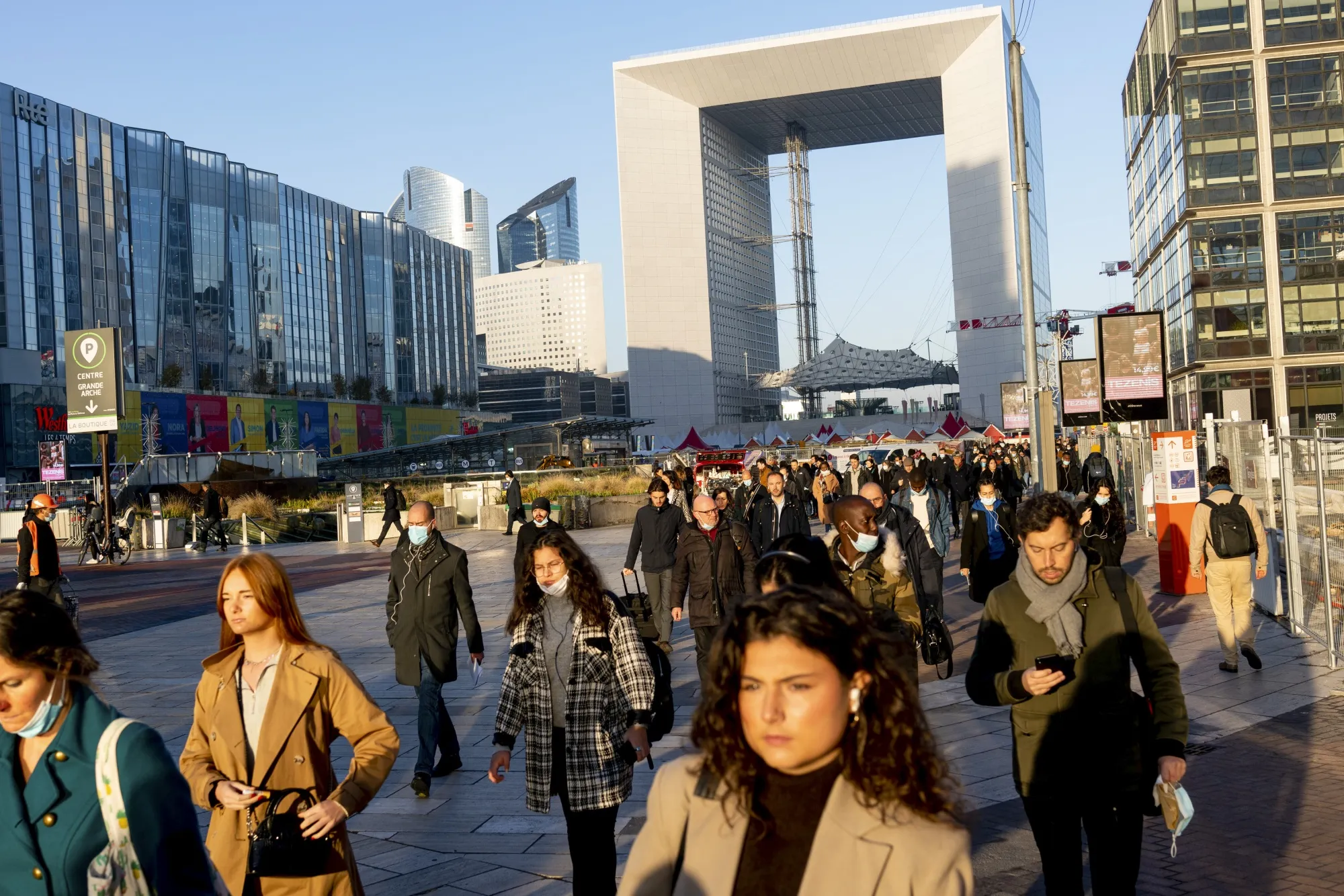 Commuters in view of the Grand Arch in the La Defense financial district of Paris.