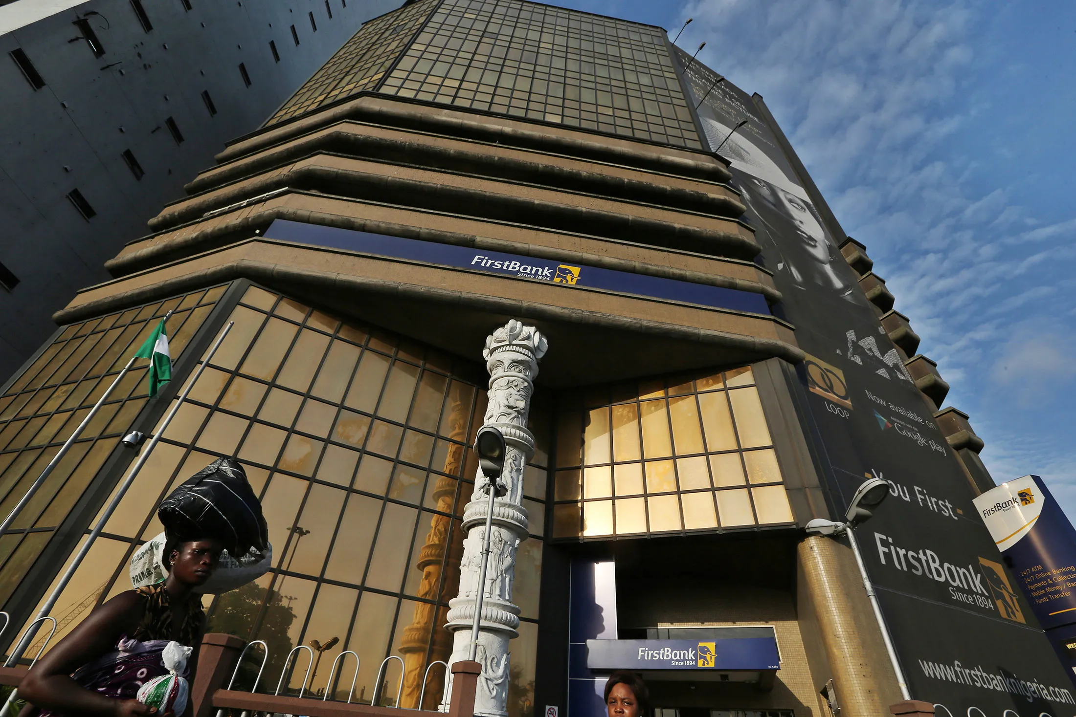 Pedestrians pass the entrance to the First Bank of Nigeria Plc head office in Lagos, Nigeria.