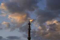 A Burning Flame From A Stack Against A Cloudy Sky