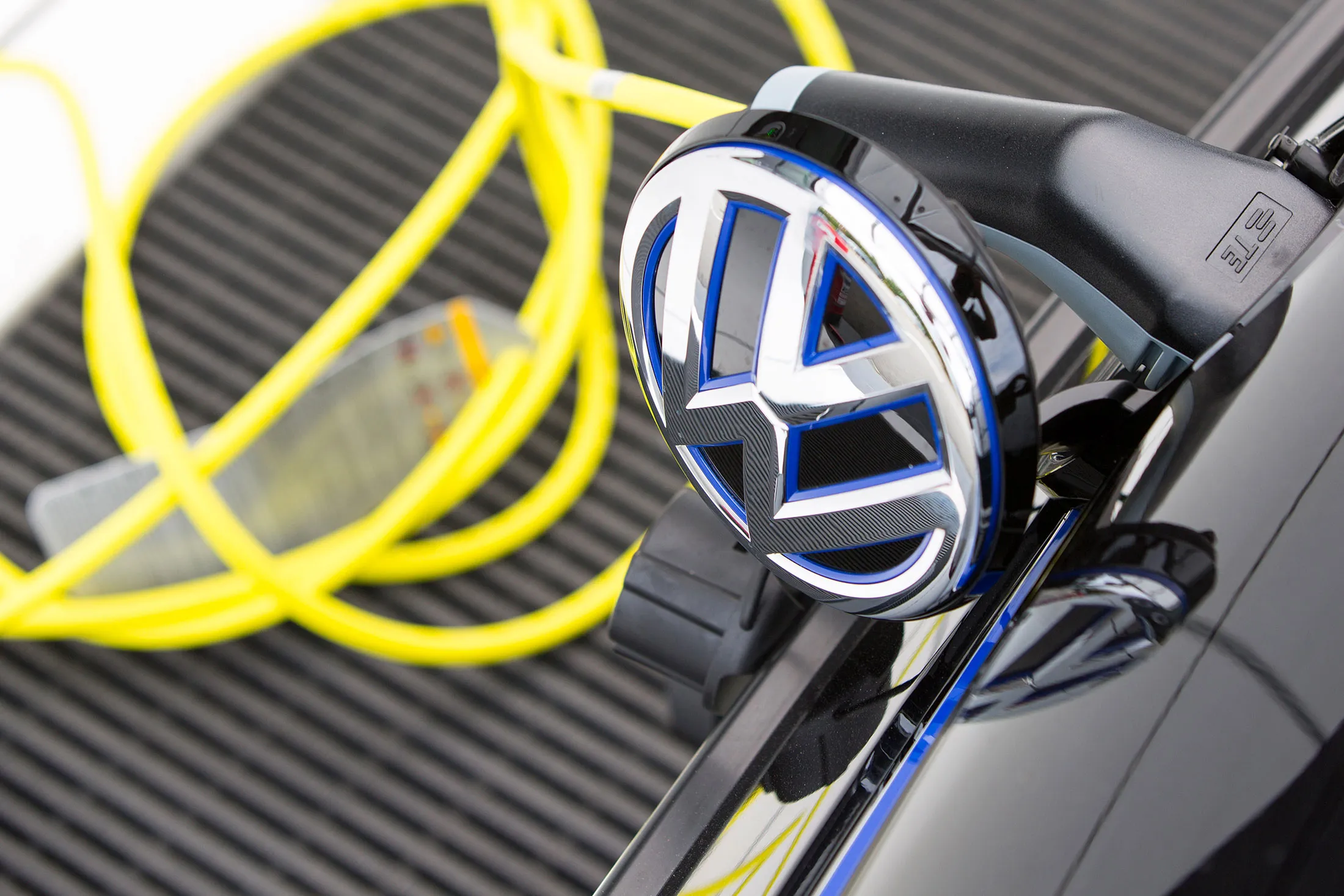A charging plug sits next to a VW badge cover.
