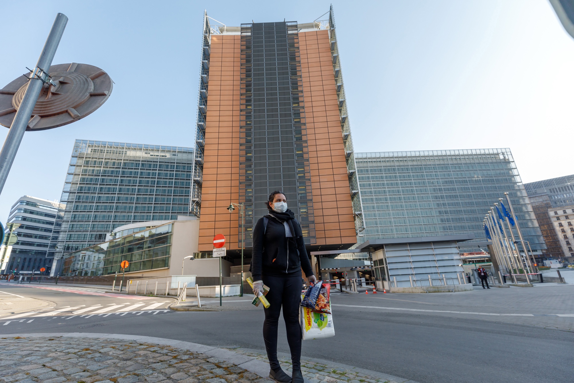 A shopper wearing a protective face mask carries groceries outside the Berlaymont building, which houses offices of the European Commission, in Brussels on March 26.