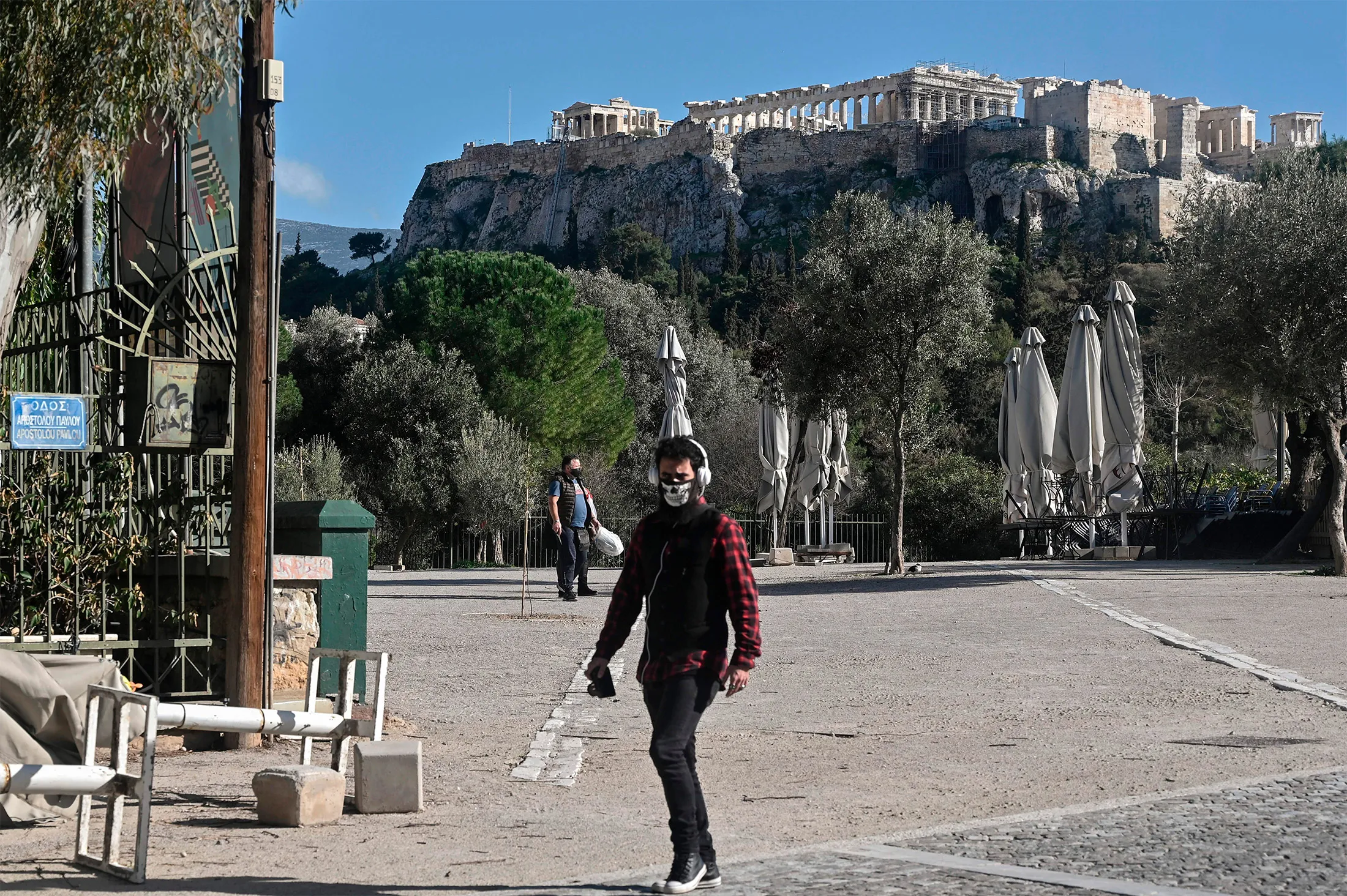 People walk past closed cafes under the Acropolis in Athens on Feb. 9.