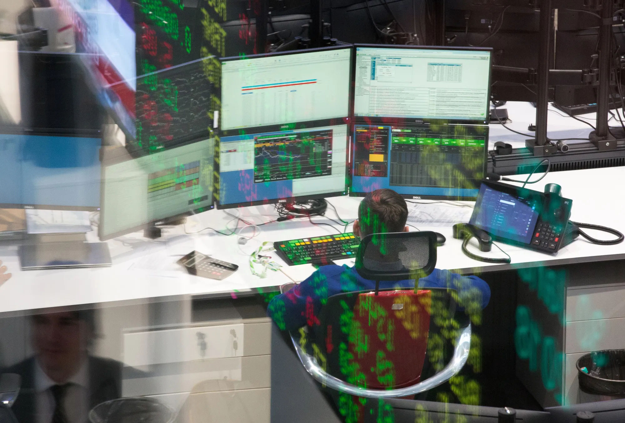 Stock price information is reflected on&nbsp;glass as a trader monitors financial data.&nbsp;