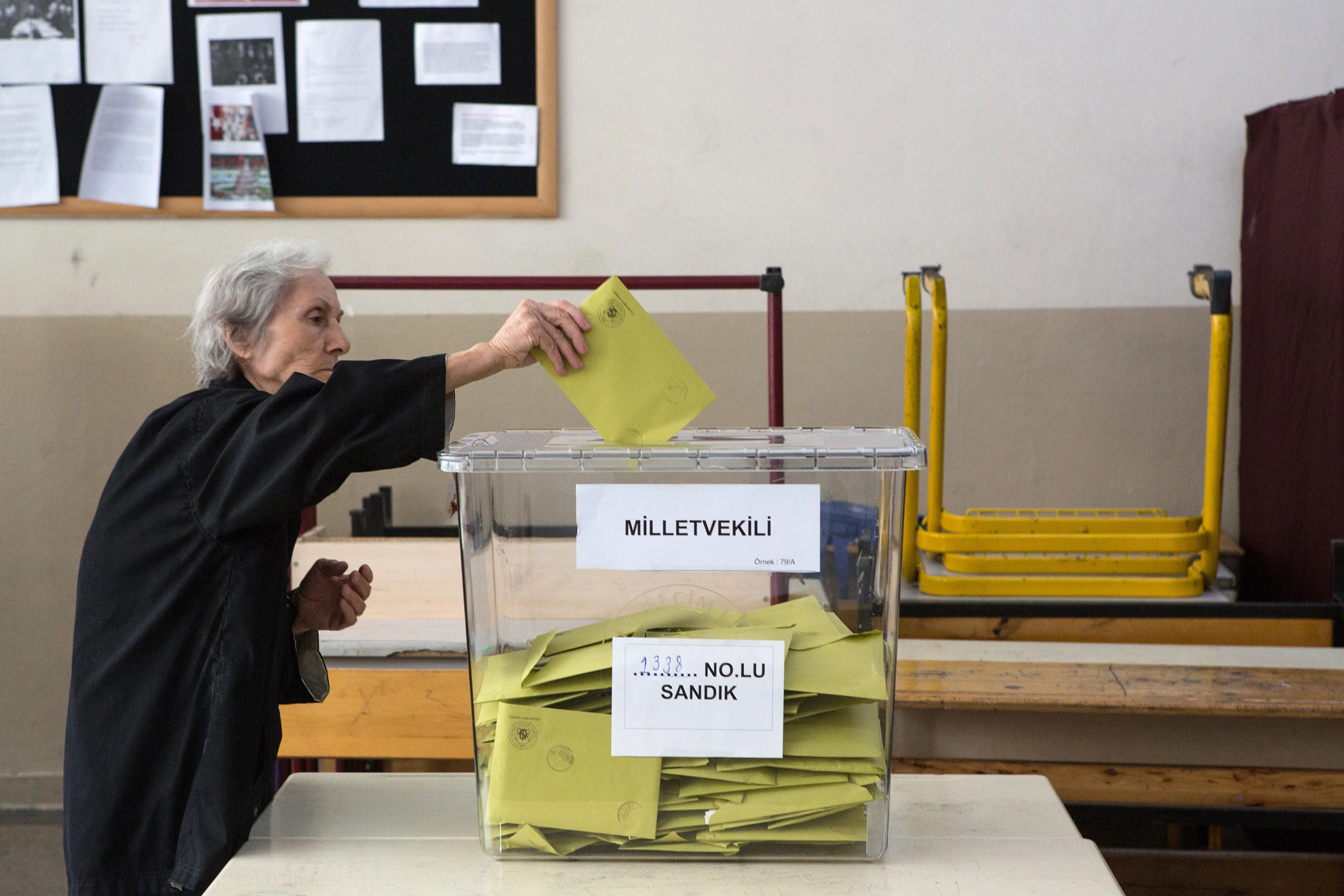 An elderly voter places her vote slip into a ballot box at a polling station in the Turkish general election in Istanbul, Turkey, on Sunday, June 7, 2015.
