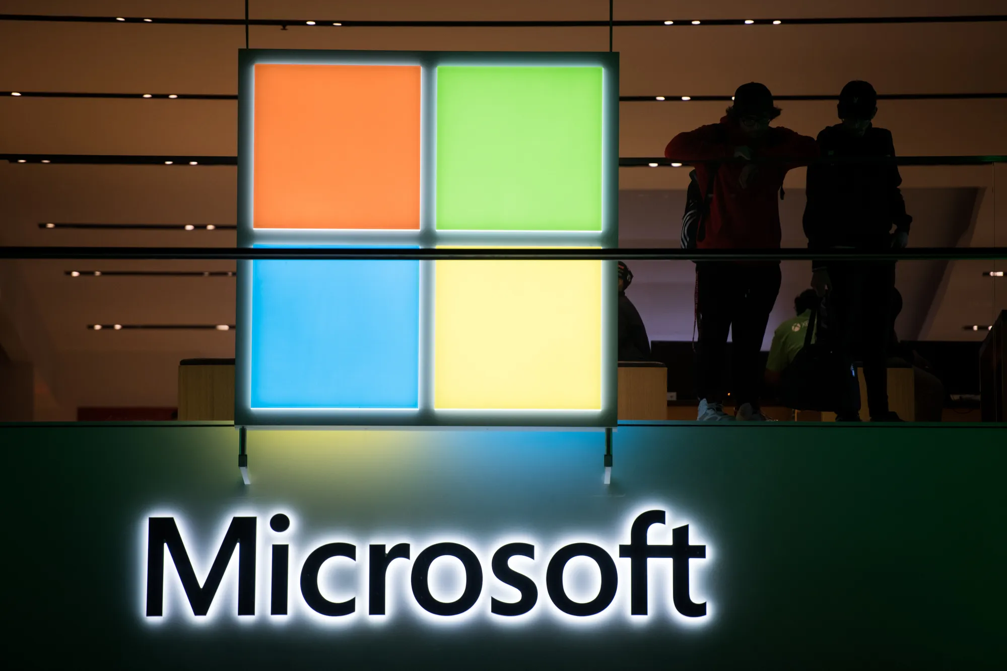 Customers stand near the Microsoft Corp. logo during the Microsoft Corp. Xbox One X game console global launch event in New York, U.S.