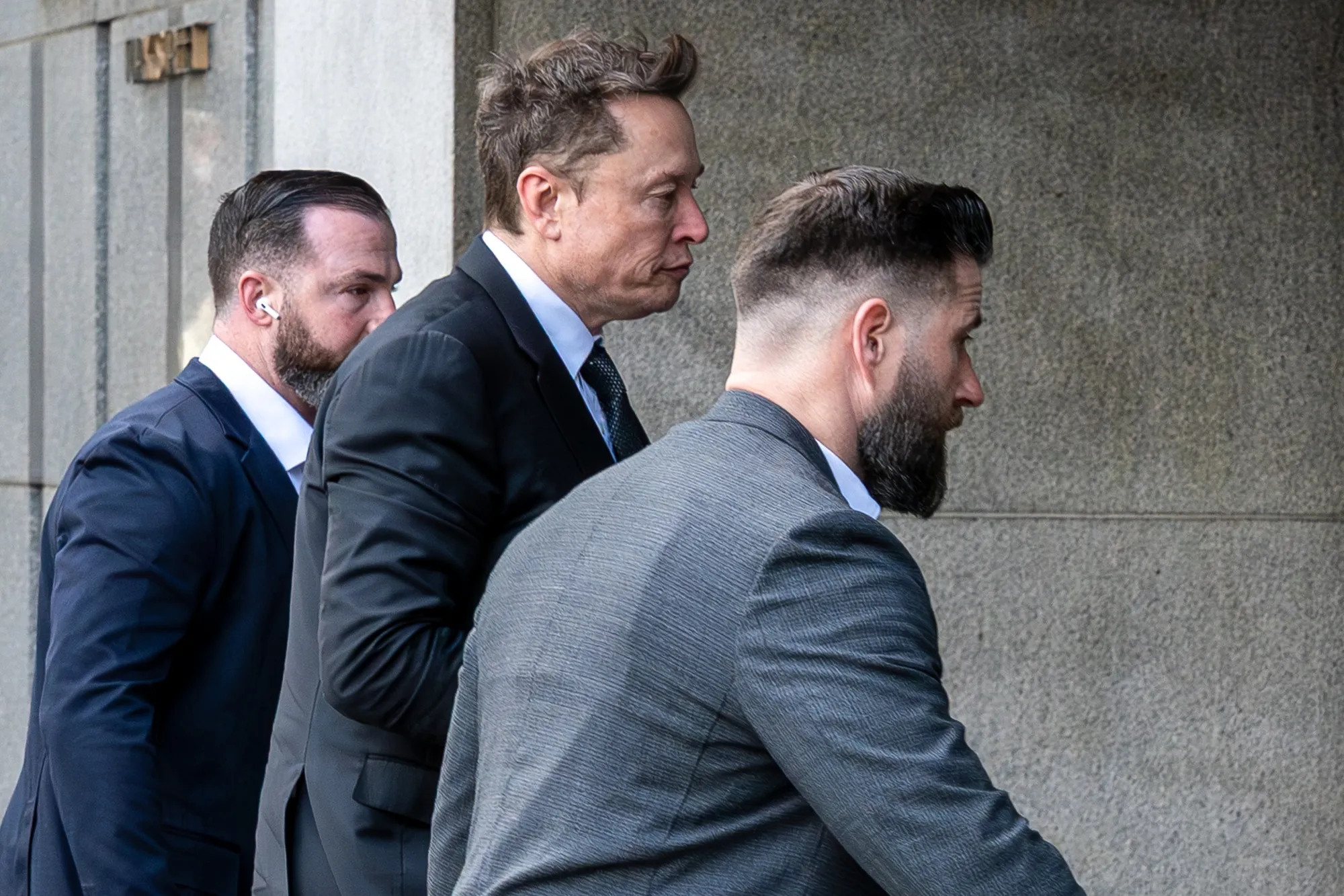 Elon Musk, center, arrives at federal court in San Francisco on March 4.
