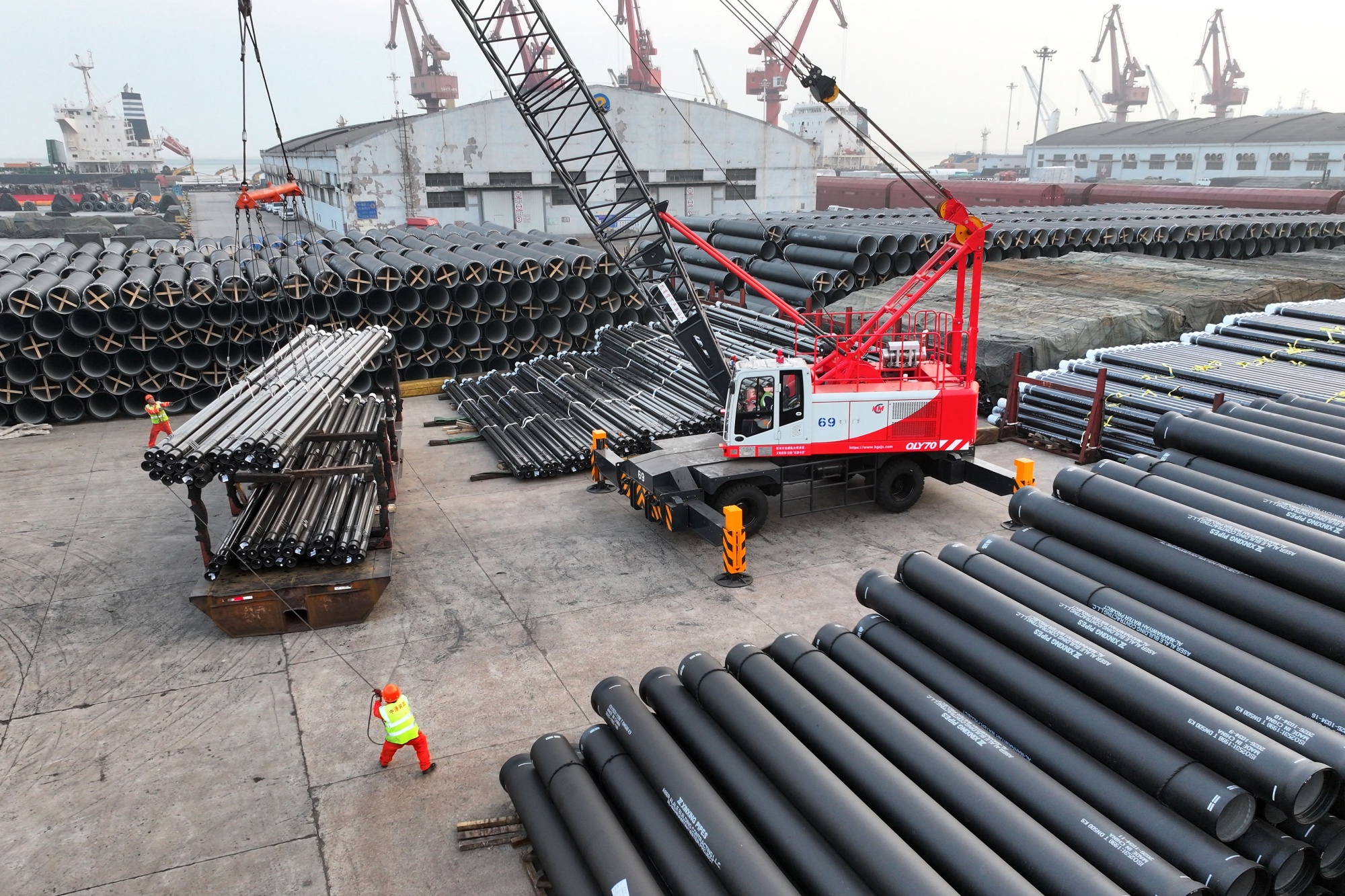 Workers load steel pipes for export at a port in Lianyungang, China.