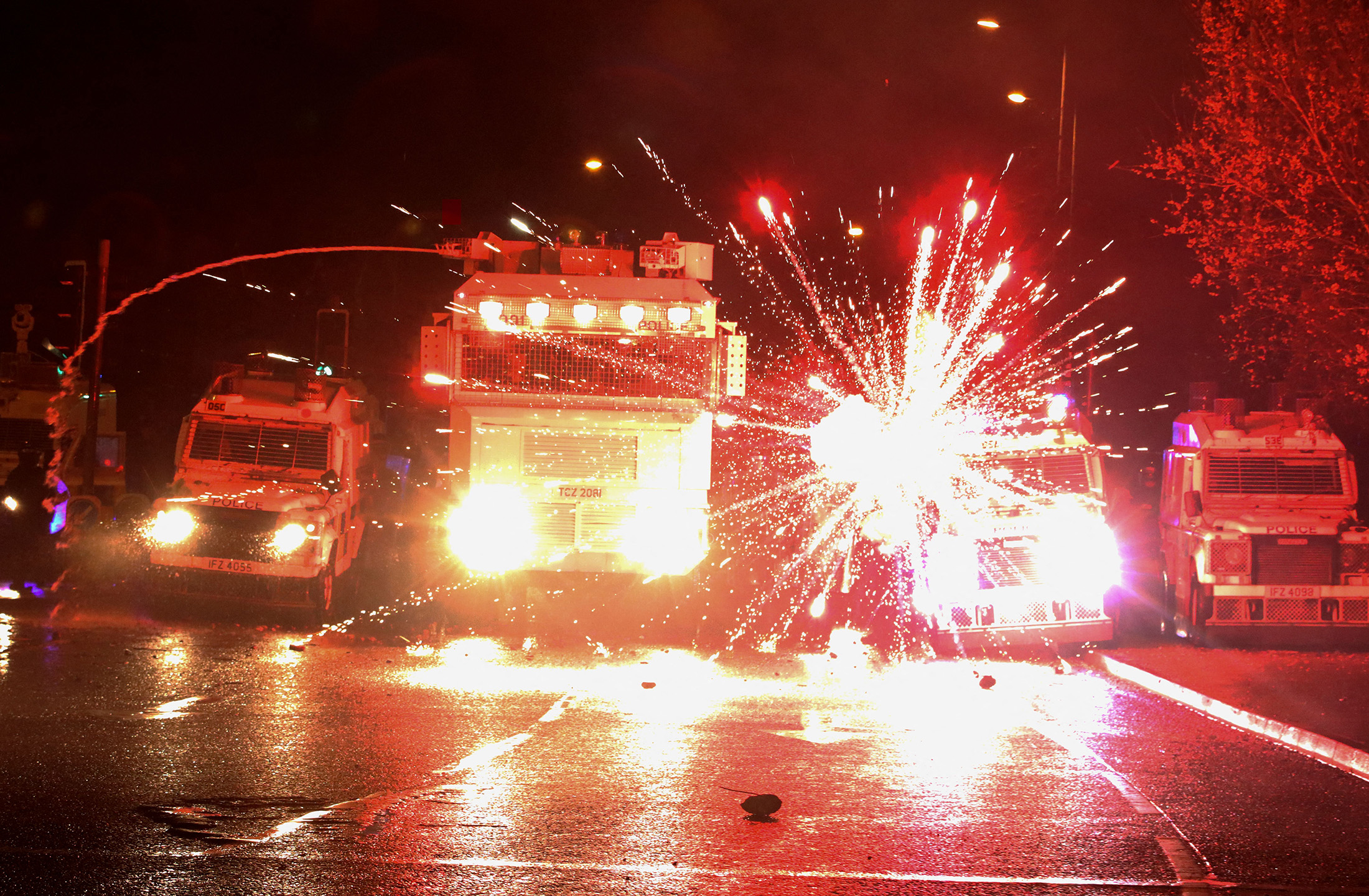 Fireworks explode at police vehicles during clashes with nationalist youths in the Springfield Road area of Belfast on April 8.