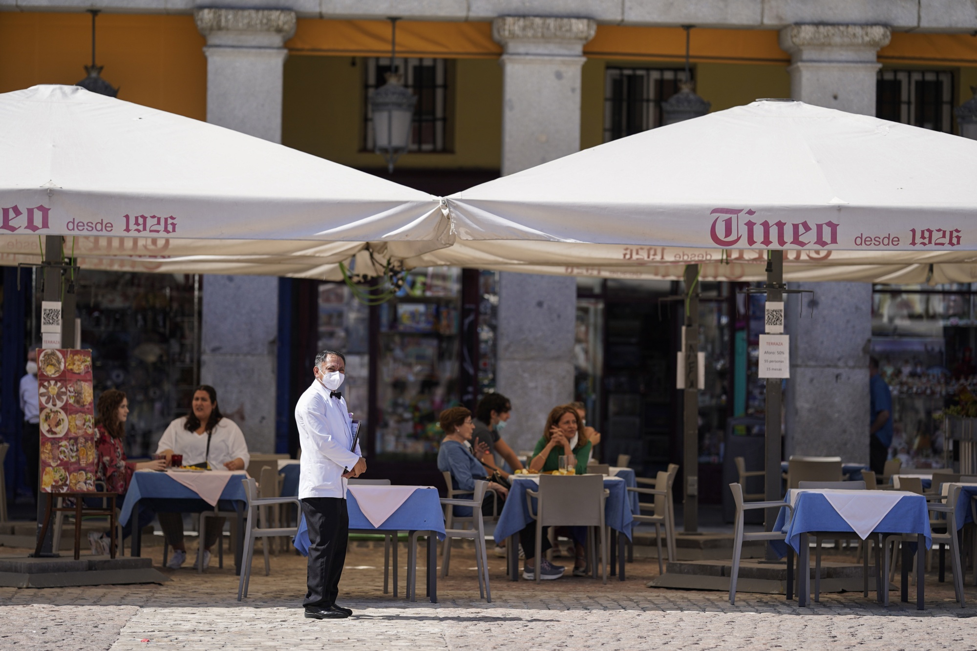 A waiter stands and waits for customers outside a restaurant on Plaza Mayor in Madrid, on Sept. 22.