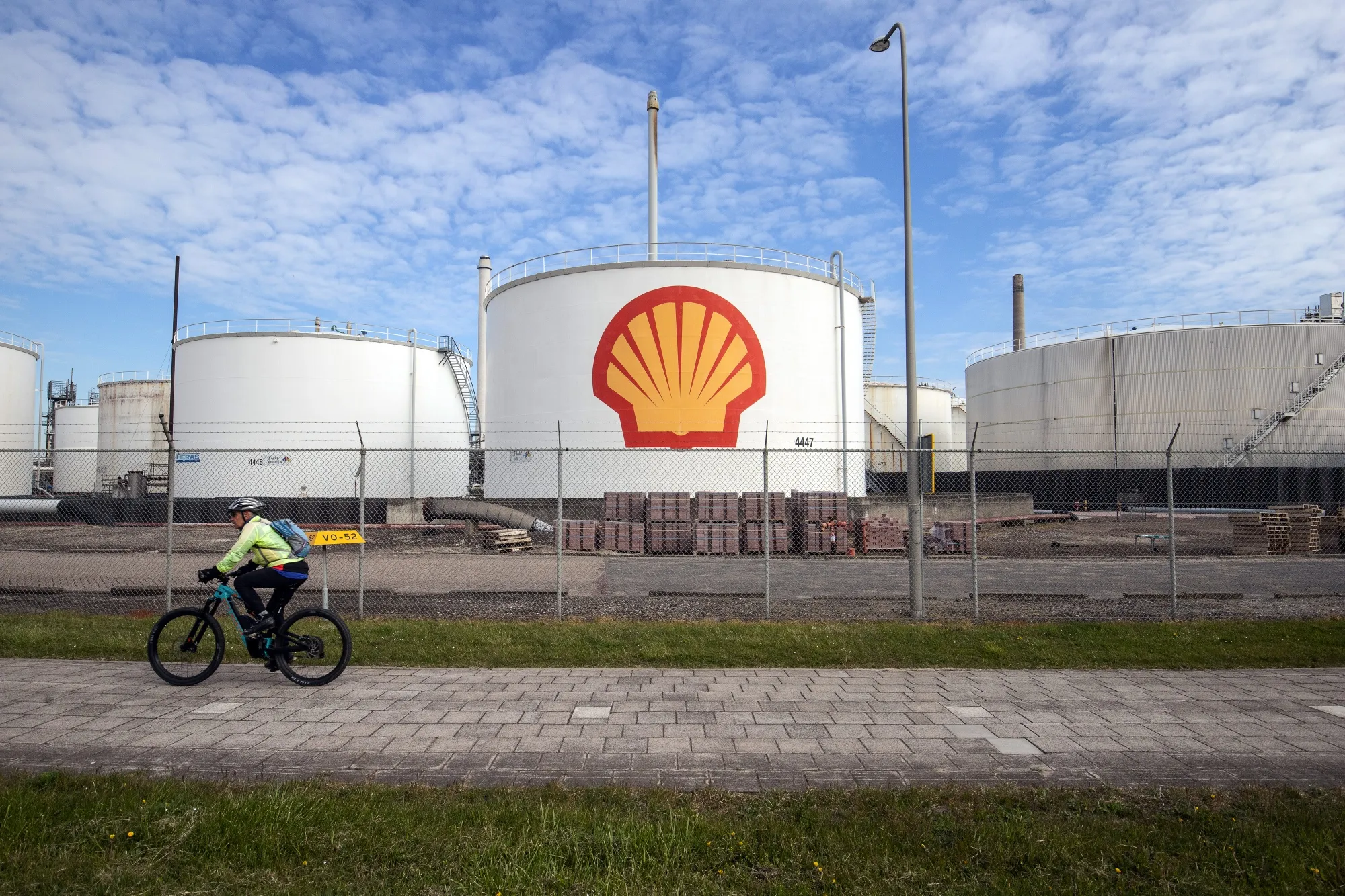A cyclist passes oil silos at a Shell Plc refinery in Rotterdam, Netherlands.
