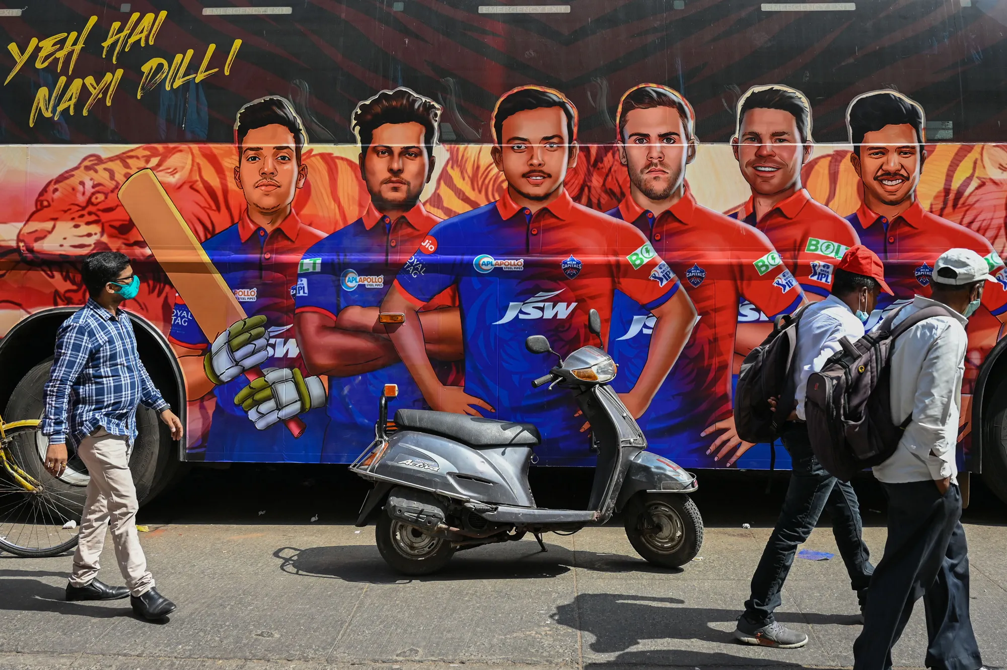 Pedestrians walk past the coach of Indian Premier League's Delhi Capitals, in Mumbai.