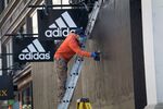 A worker removes screws from wood boarded up on the windows of an Adidas AG store in San Francisco, California, on June 16.