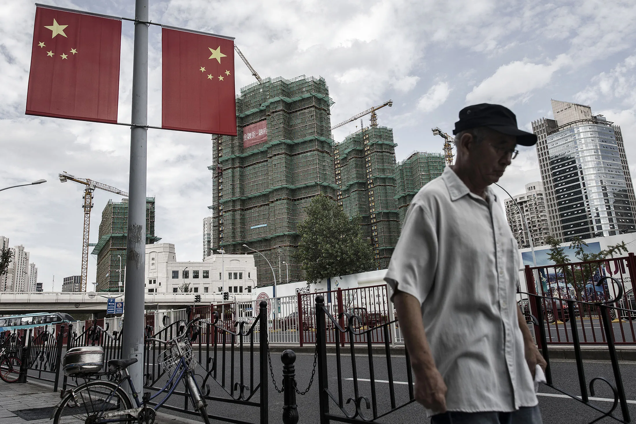 A pedestrian walks past Chinese national flags hanging on a street light in Shanghai, China.
